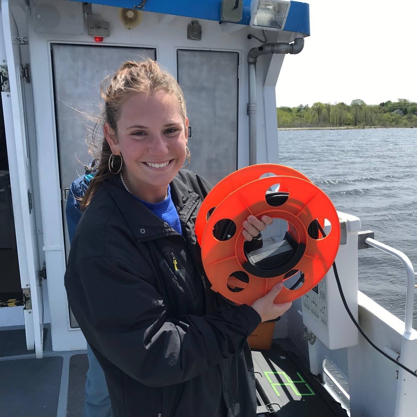 Allison onboard the W.G. Jackson research vessel holding a data cable.